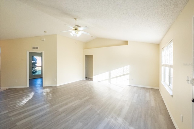 empty room featuring plenty of natural light, ceiling fan, a textured ceiling, and vaulted ceiling