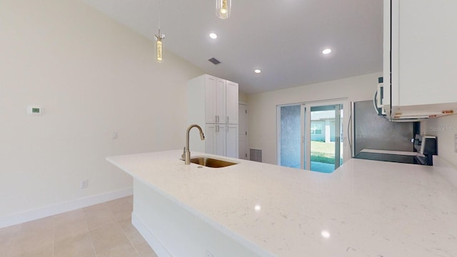 kitchen with light stone countertops, sink, decorative light fixtures, white cabinets, and range