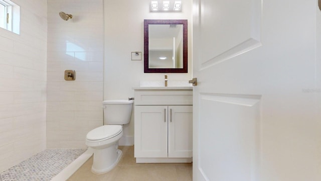 bathroom featuring tile patterned floors, vanity, a tile shower, and toilet