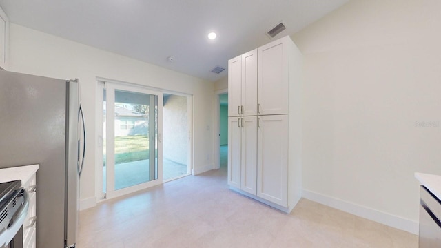 kitchen featuring stainless steel refrigerator, stove, and white cabinets