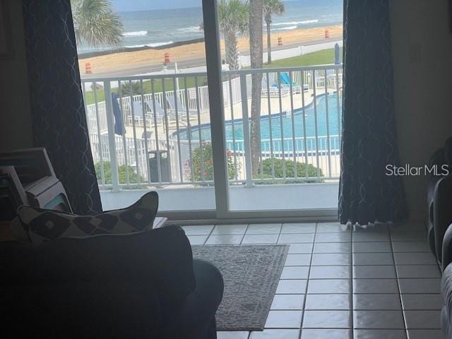 interior space with tile patterned floors, a water view, and a beach view