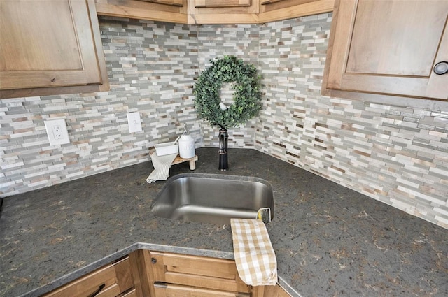 details featuring sink, backsplash, and dark stone countertops