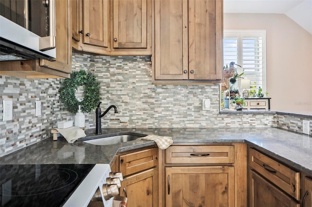 kitchen featuring tasteful backsplash, sink, dark stone counters, and white stove