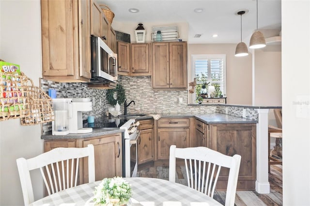 kitchen with pendant lighting, white electric range oven, kitchen peninsula, and tasteful backsplash