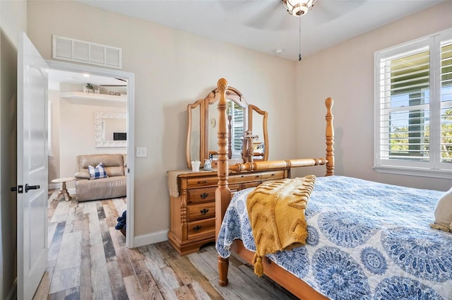 bedroom with multiple windows, ceiling fan, and hardwood / wood-style floors