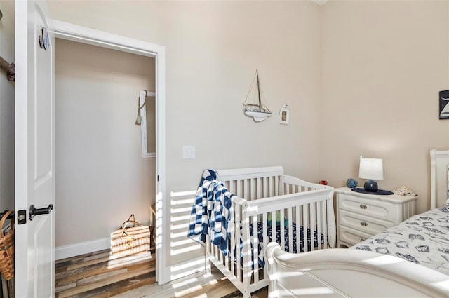 bedroom with a nursery area and wood-type flooring