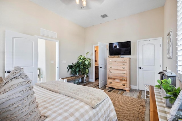 bedroom with ceiling fan, light hardwood / wood-style flooring, and a high ceiling