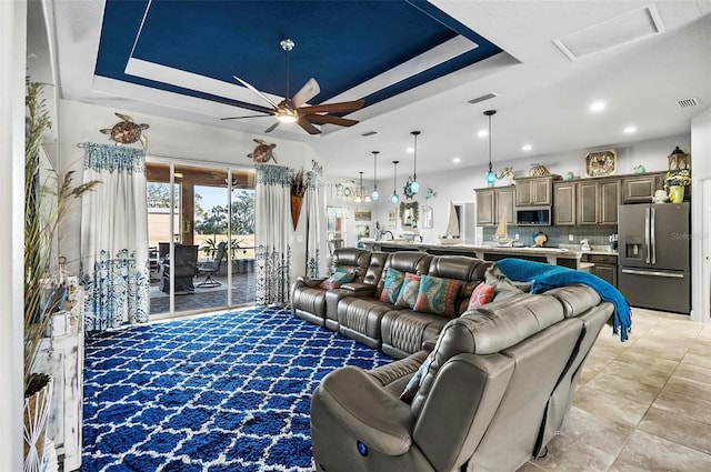 living room featuring ceiling fan and a tray ceiling