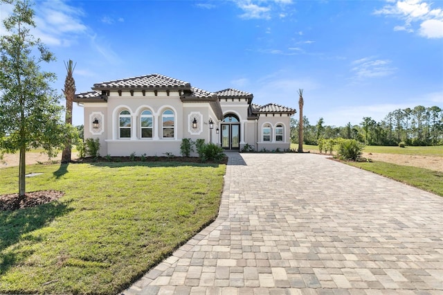 mediterranean / spanish-style house featuring a front lawn and french doors