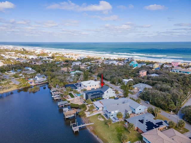 drone / aerial view featuring a water view, a residential view, and a beach view