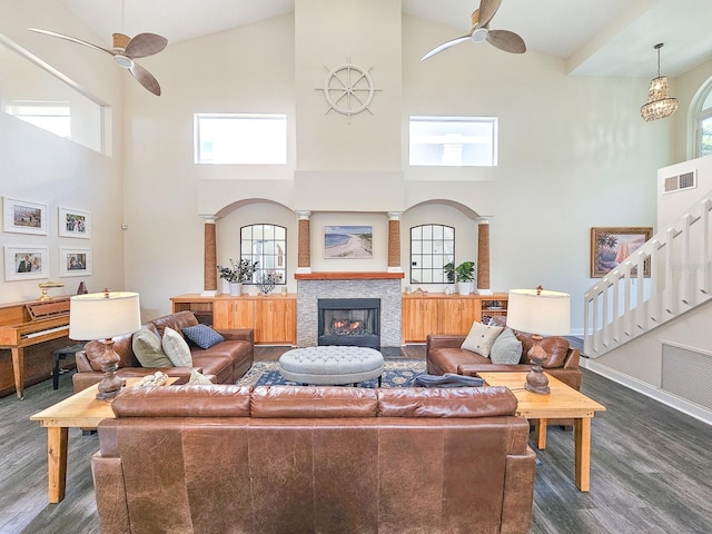 living room with dark hardwood / wood-style flooring, a towering ceiling, and ceiling fan