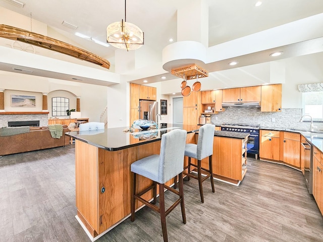 kitchen with pendant lighting, high end appliances, dark wood-type flooring, decorative backsplash, and a kitchen island