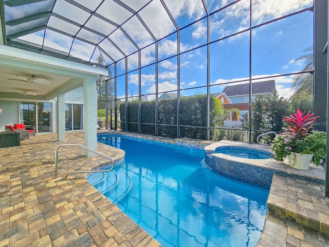 view of swimming pool with glass enclosure, ceiling fan, a patio area, and an in ground hot tub