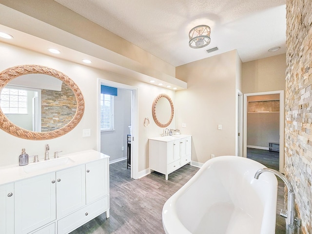 bathroom featuring hardwood / wood-style flooring, vanity, a bath, and a textured ceiling