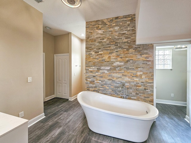 bathroom with a bathing tub, wood-type flooring, and a textured ceiling