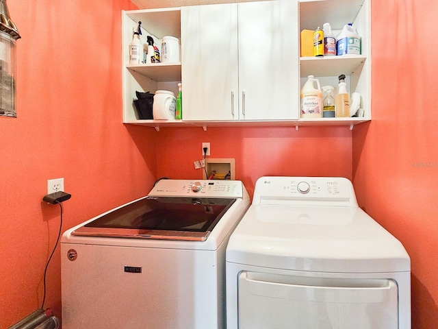 clothes washing area with cabinets and independent washer and dryer