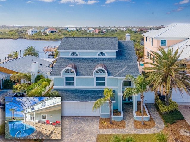 view of front of home featuring decorative driveway, stucco siding, a shingled roof, a water view, and a residential view