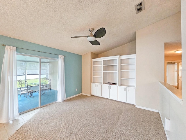 empty room with vaulted ceiling, light colored carpet, ceiling fan, and a textured ceiling