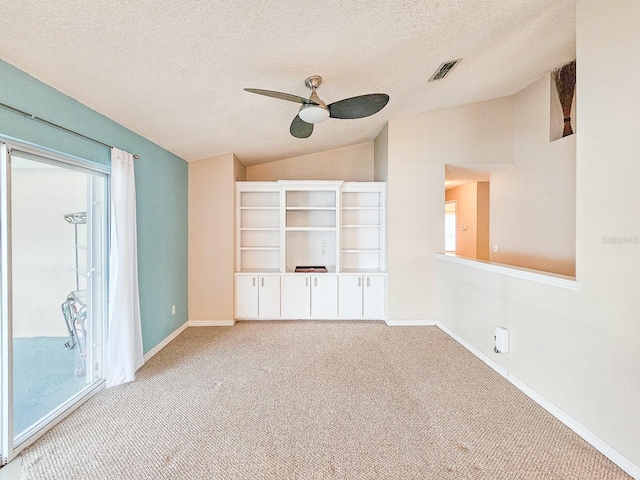 interior space featuring a textured ceiling, ceiling fan, vaulted ceiling, and light colored carpet