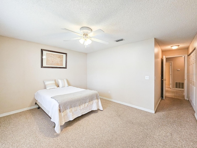 carpeted bedroom featuring ceiling fan and a textured ceiling