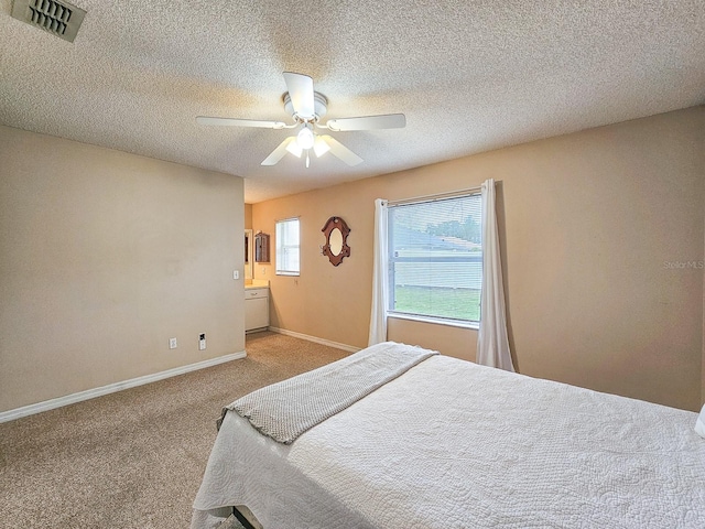 bedroom with ceiling fan, carpet, and a textured ceiling