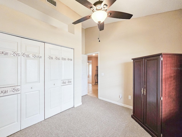 unfurnished bedroom featuring ceiling fan, light colored carpet, and a closet