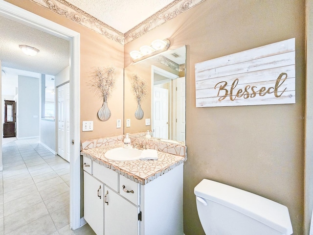 bathroom with a textured ceiling, tile patterned floors, vanity, and toilet