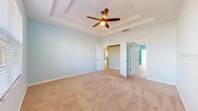 carpeted empty room featuring ceiling fan and a tray ceiling