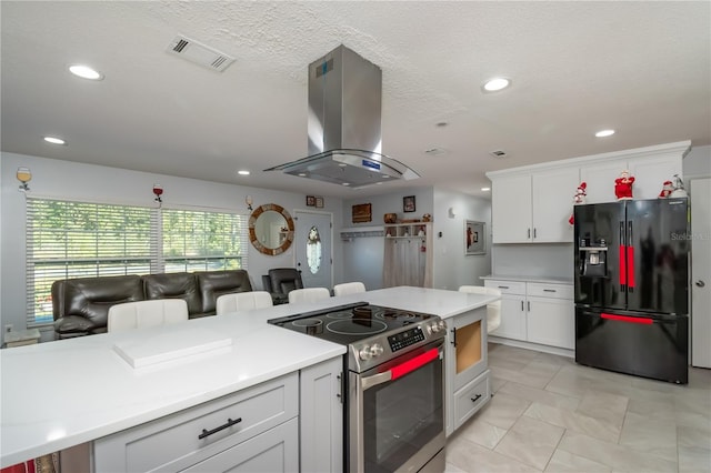 kitchen featuring stainless steel electric range oven, a breakfast bar, white cabinetry, island exhaust hood, and black fridge