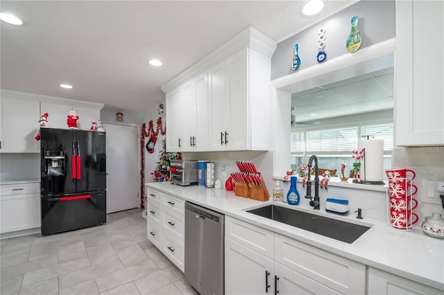 kitchen with white cabinetry, sink, stainless steel dishwasher, and black fridge