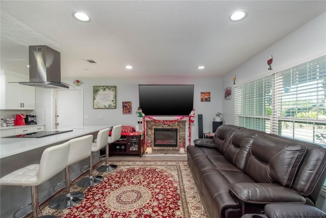 living room featuring a premium fireplace, a textured ceiling, and light hardwood / wood-style floors