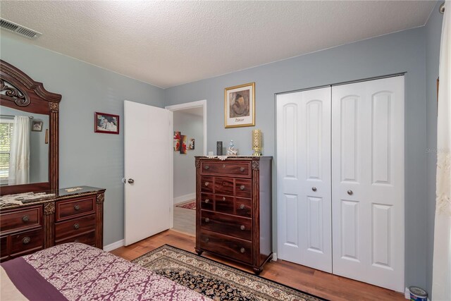 bedroom featuring a textured ceiling, light wood-type flooring, and a closet