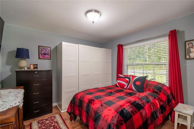 bedroom featuring a closet, a textured ceiling, and light hardwood / wood-style flooring