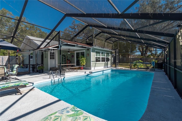 view of swimming pool featuring a patio, ceiling fan, and glass enclosure