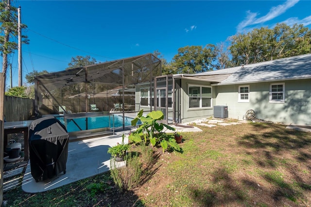 rear view of property featuring a fenced in pool, a yard, central AC, a patio, and glass enclosure