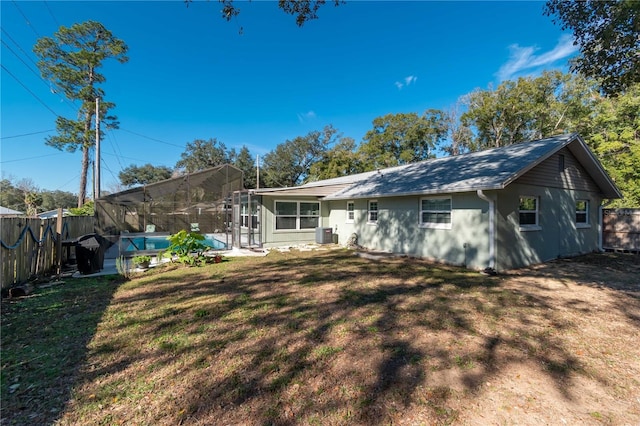 rear view of property featuring cooling unit, a fenced in pool, a yard, and glass enclosure