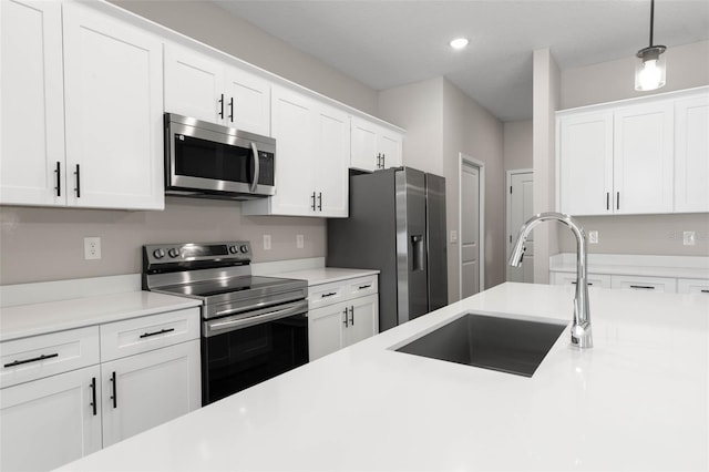 kitchen featuring sink, stainless steel appliances, hanging light fixtures, and white cabinets