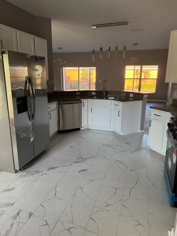 kitchen with kitchen peninsula, appliances with stainless steel finishes, sink, and white cabinetry