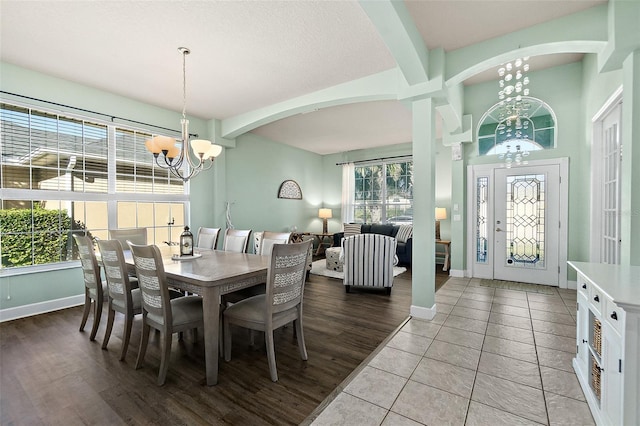 tiled dining area with a healthy amount of sunlight, beamed ceiling, and a chandelier