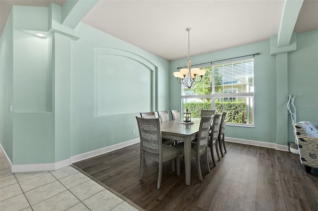 dining space with beamed ceiling, light hardwood / wood-style floors, and an inviting chandelier