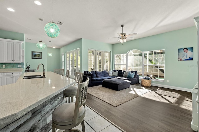 living room featuring ceiling fan, sink, and light hardwood / wood-style floors