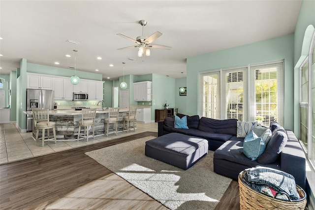 living room featuring ceiling fan, light hardwood / wood-style floors, and sink