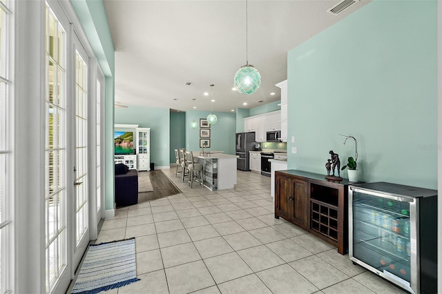 kitchen featuring stainless steel appliances, light tile patterned floors, white cabinets, wine cooler, and hanging light fixtures