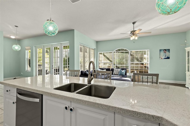 kitchen with light stone counters, ceiling fan, sink, pendant lighting, and white cabinetry