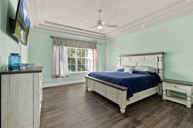 bedroom with a tray ceiling, ceiling fan, and dark hardwood / wood-style floors