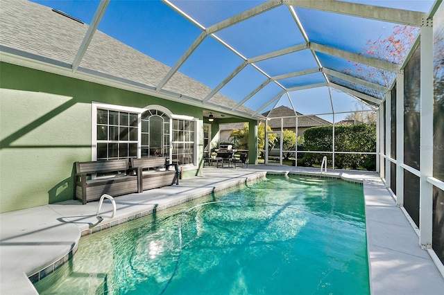 view of swimming pool featuring glass enclosure, ceiling fan, and a patio area