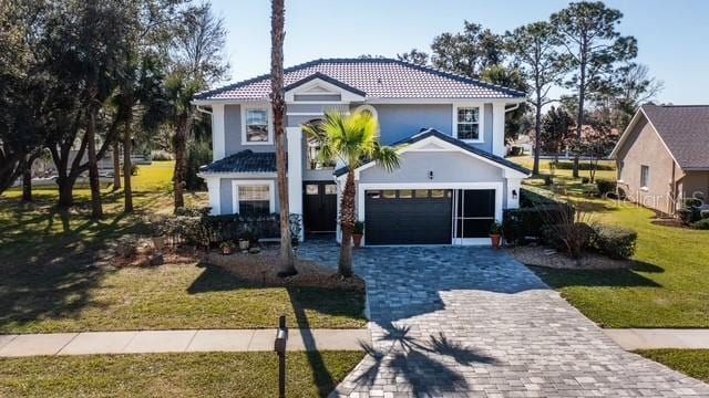 mediterranean / spanish house featuring a garage and a front lawn