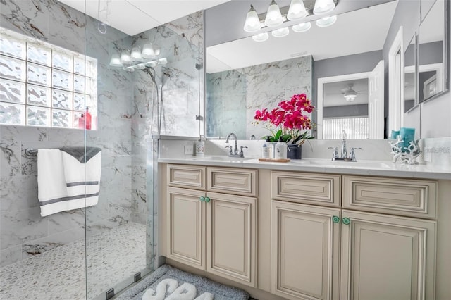 bathroom with a tile shower, vanity, and a healthy amount of sunlight