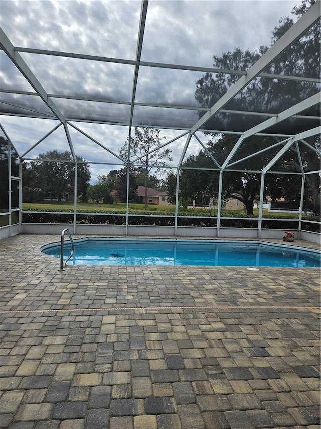 view of pool with glass enclosure and a patio area