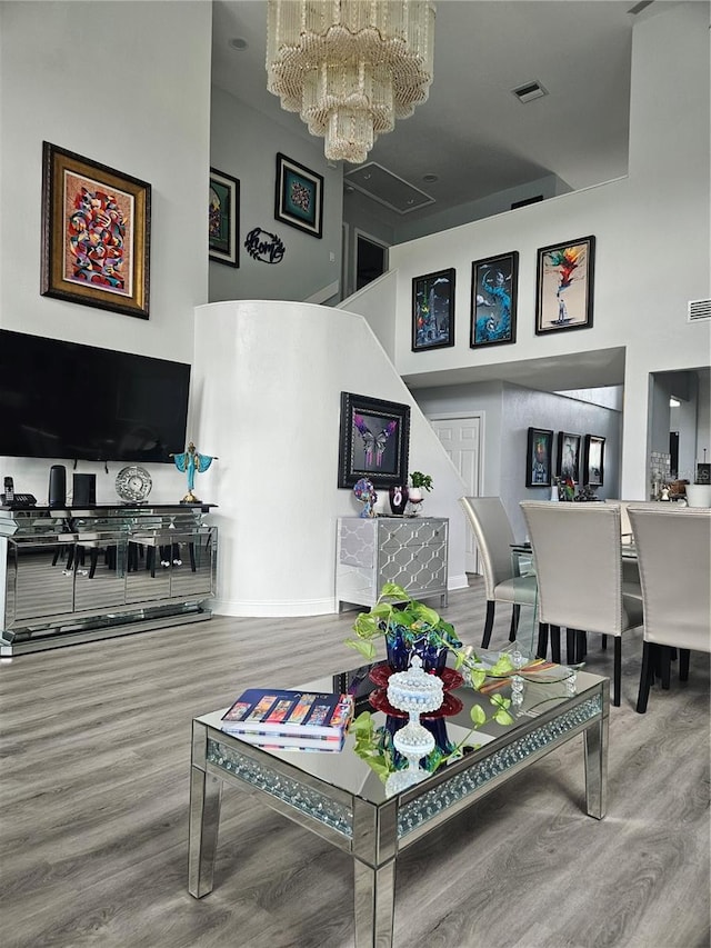 living room featuring hardwood / wood-style floors, a chandelier, and a high ceiling